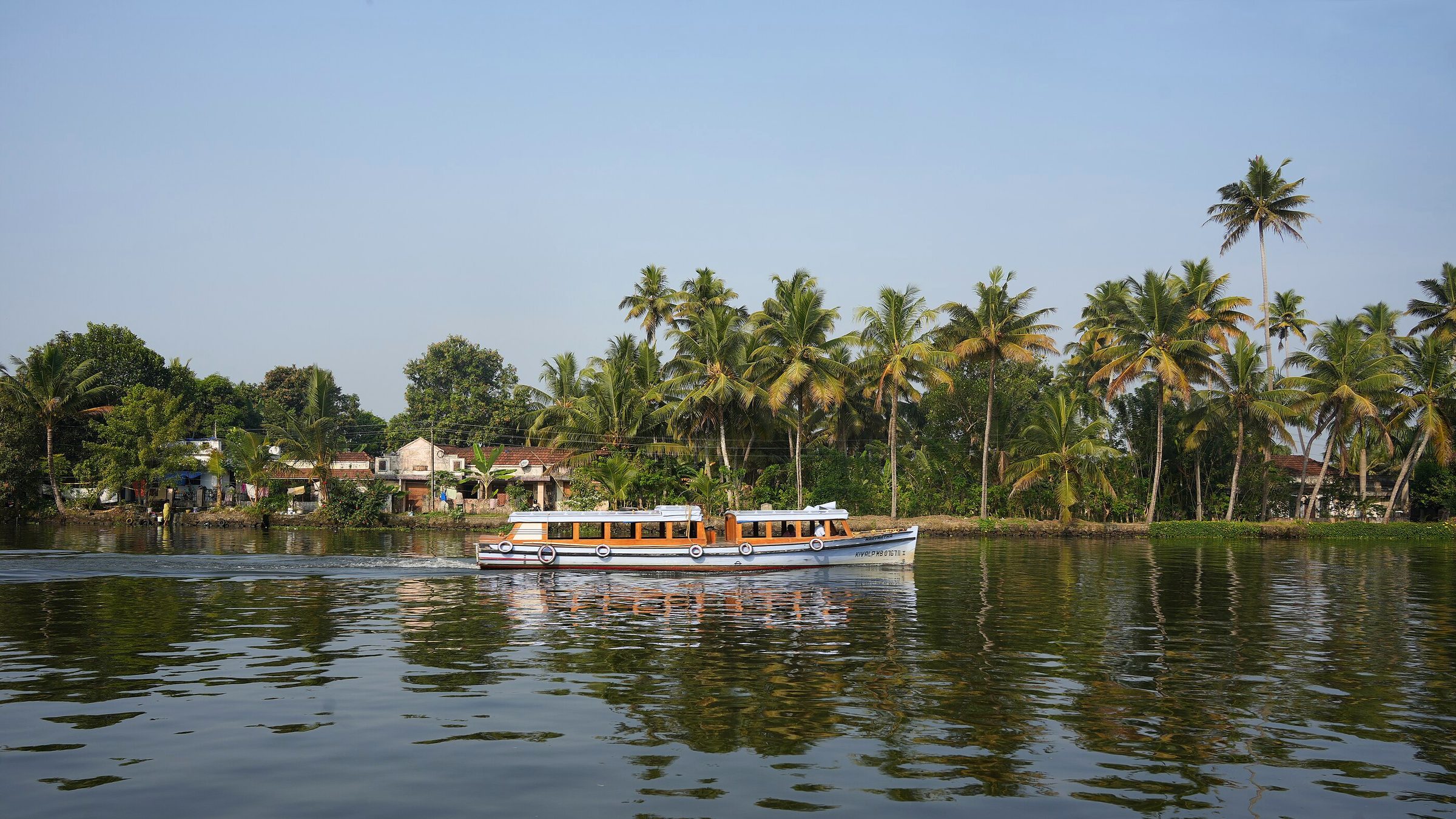 A passenger boat crossing the Kerala backwaters under coconut palms