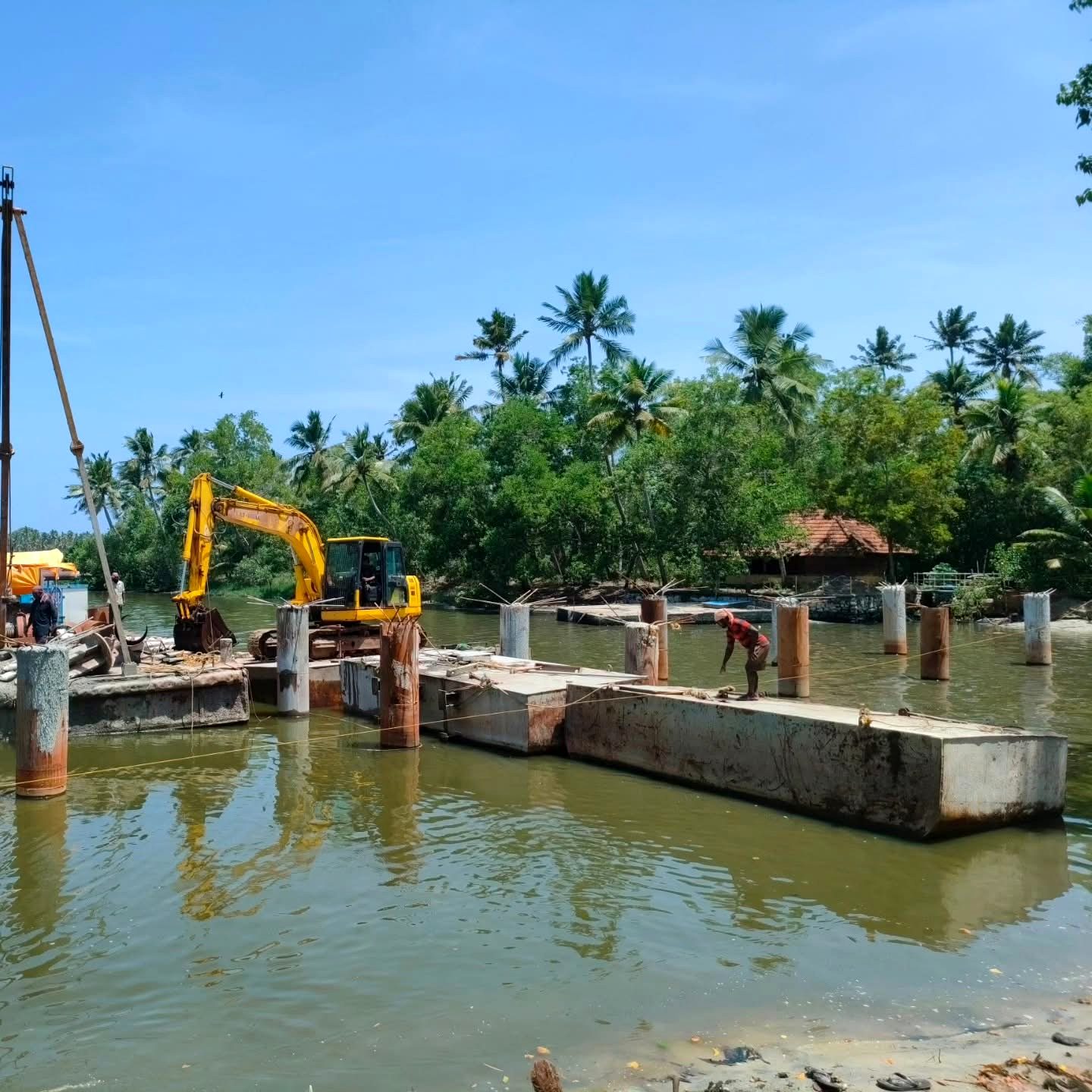 Excavator working from a barge over concrete pile caps in the backwater